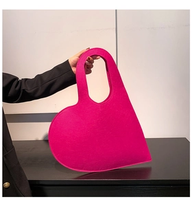 Detail of hot pink heart-shaped felt handbag showing reinforced stitching and cutout handle