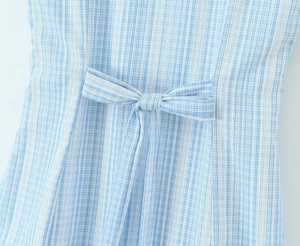 Close-up of blue and white plaid dress featuring a decorative bow tie and lace texture