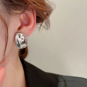 Macro view of minimalist irregular liquid metal silver studs on a female model's ear