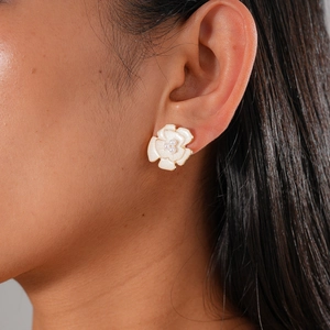 Detailed shot of floral stud earring with white petals, gold edges, and pearl centers