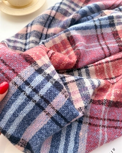 Close-up of soft plaid scarf texture in pink and blue with a focus on knitted fabric