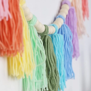 Macro detail of bohemian garland with natural wood beads and colorful yarn tassels