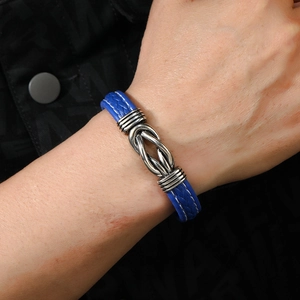 Close-up of blue braided leather bracelet with silver infinity clasp on man's wrist