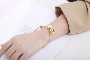 Detail van een verstelbare gouden armband met 'True Love' en hartbedels op een boek