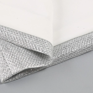 Detailed macro view of white fabric with dense silver sequin trim and high-quality stitching
