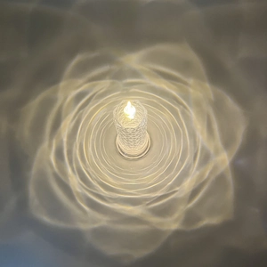 Top view of crystal LED candle lamp projecting warm rose petal light patterns on the surface