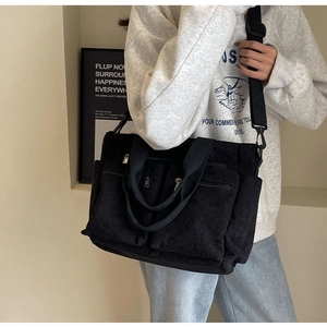 Detail view of black corduroy crossbody bag with adjustable strap on a model