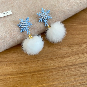 Detail of blue snowflake earrings with small pearls and soft white plush pom-pom drops
