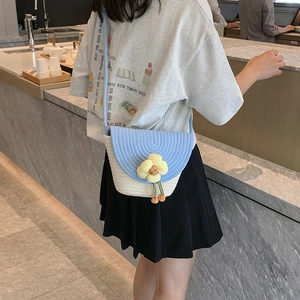 Detail of a blue and white woven straw bucket bag with a yellow flower charm decoration