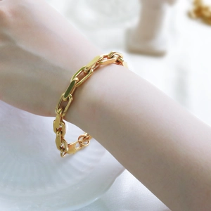Detail view of a chunky gold Cuban chain bracelet worn on the wrist for a trendy look