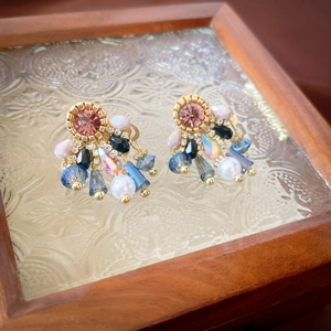 Gros plan de boucles d'oreilles vintage avec cristaux roses et perles sur plateau