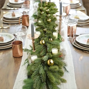 Faux evergreen Christmas garland with golden ornaments used as a festive table runner