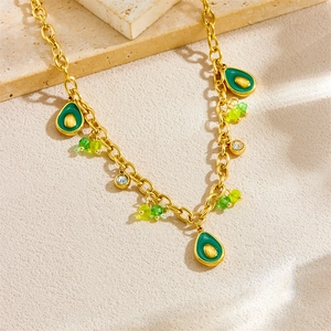 Collier doré avec pendentifs avocat, perles vertes et cristaux brillants sur un support