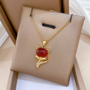 Macro view of gold titanium fox pendant with red stone and pavé crystal details