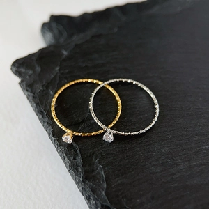 Macro detail of gold and silver textured rings with tiny zircons on black slate