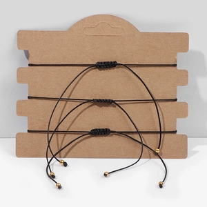 Detailed view of three handmade black woven bracelets with adjustable cords and gold beads