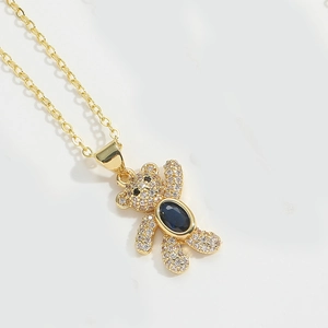 Close-up of golden bear pendant with blue oval gemstone and white zircon pavé details