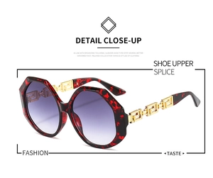 Detail of red tortoiseshell octagonal frame with gold Greek meander pattern on the temples