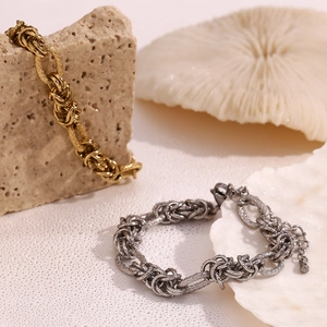 Detail of chunky 14K gold and silver knot chains on natural textured stone background