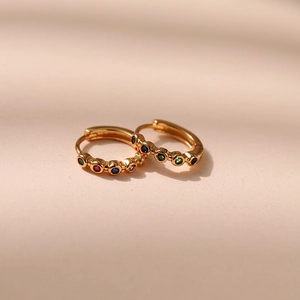 Close-up of gold plated small hoop earrings with colorful rainbow cubic zirconia