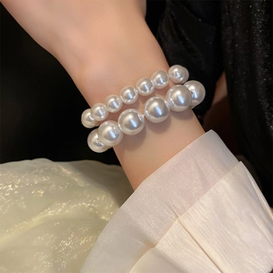 Close-up of double-layer white pearl elastic bracelet on wrist with elegant silk sleeve