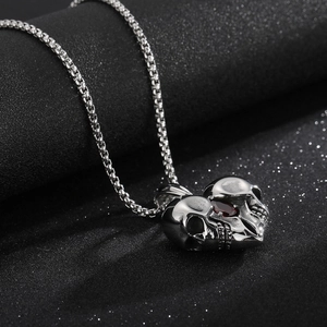 Macro view of punk silver skull heart pendant with red crystal on a box chain