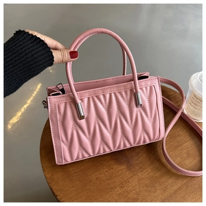 Detail of pink quilted PU leather handbag with elegant metal chain strap connectors