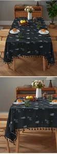 Detail of black Christmas tablecloth with white reindeer embroidery and tassel fringe edges
