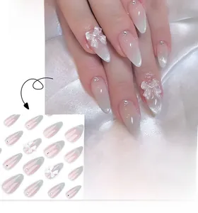 Detail view of pink gradient almond press-on nails with 3D bows and rhinestones