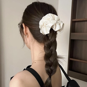 Détail d'un chouchou en dentelle blanche ornant une tresse pour un style élégant et doux