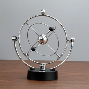 Newton's cradle kinetic desk toy with silver metal frame and black base on wooden surface