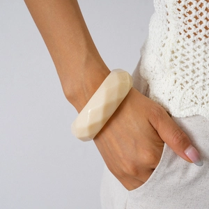 Close-up of beige geometric faceted resin bangle worn with minimalist style clothing