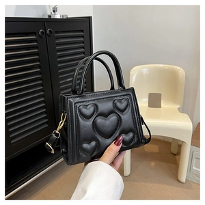Détail du sac à main noir avec cinq motifs de cœur en relief et texture en cuir