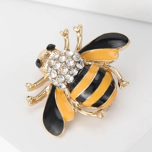 Macro shot of bee brooch featuring gold metal, yellow black enamel and clear rhinestones