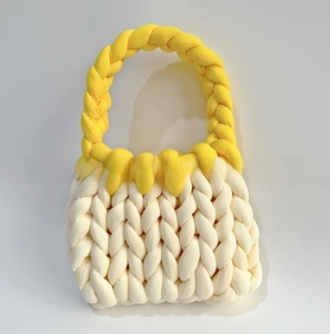 Detail of hand-woven chunky knit handbag in yellow and beige cotton yarn texture