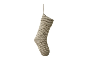 Detailed close-up of beige knitted Christmas stocking with textured crochet patterns