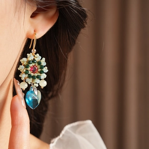 Dettaglio di orecchini vintage a fiore con gemma a goccia blu indossati da modella
