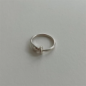Detailed view of 925 sterling silver minimalist knot ring on a grey textured surface