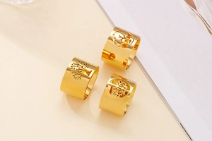 Detailed view of three gold-plated wide hollow rings featuring intricate tree of life patterns