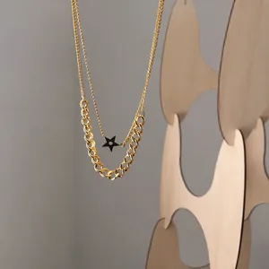 Detail of double-layer gold chain necklace featuring a black star pendant on wood
