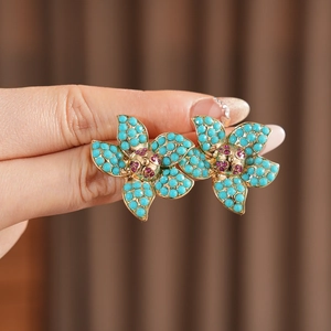 Macro view of vintage flower earrings with blue turquoise petals and red crystal core