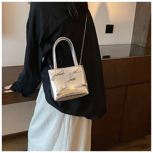 Detailed view of silver minimalist handbag with bow decor and fine chain strap