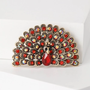 Macro shot of peacock brooch featuring sparkling red rhinestones and golden metal details