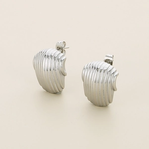 Close-up of silver-tone stainless steel stud earrings with irregular vertical textures