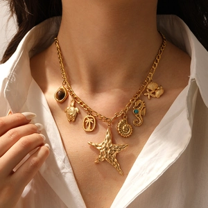 Close-up of a gold starfish and sea turtle charm necklace on a female model