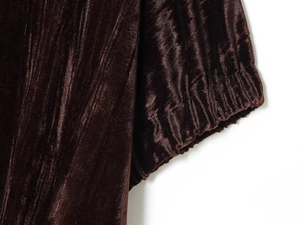 Détail du tissu en velours marron foncé montrant les poignets élastiques et la texture douce
