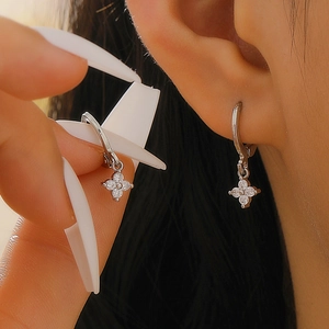 Close-up of a silver clover drop earring with sparkling zircons on a model's ear