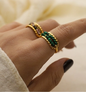 Detailed close-up of gold titanium steel rings set with green malachite and tourmaline beads