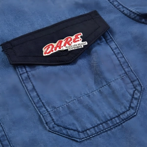 Creative D.A.R.E. metal enamel pin badge attached to a blue jacket pocket flap