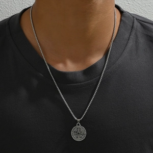 Close-up of a silver compass medallion necklace with small diamonds on a male model